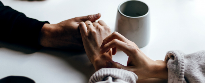 2 people holding hands across a table
